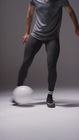 Vertical-Video-Close-Up-Studio-Shot-Of-Female-Footballer-Wearing-Sports-Clothing-Controlling-Ball-With-Feet